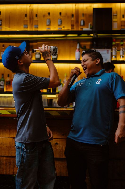Dos amigos cantando karaoke en una fiesta